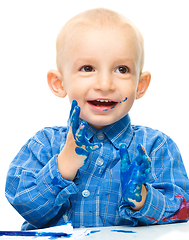 Image showing Little boy is playing with paints