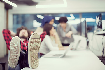 Image showing software developer resting with legs on desk