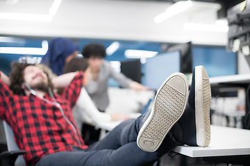 Image showing software developer resting with legs on desk