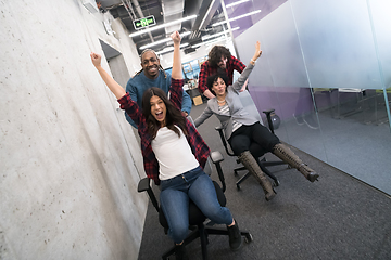 Image showing multiethnics business team racing on office chairs