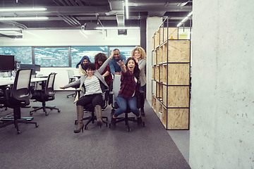 Image showing multiethnics business team racing on office chairs