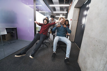 Image showing multiethnics business team racing on office chairs