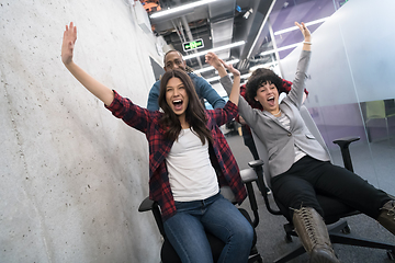 Image showing multiethnics business team racing on office chairs