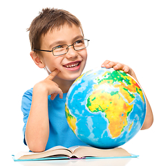 Image showing Little boy is holding globe while daydreaming