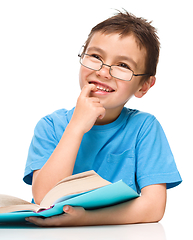 Image showing Young boy is daydreaming while reading book