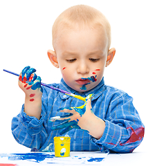 Image showing Little boy is playing with paints