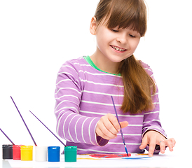 Image showing Little girl is painting with gouache