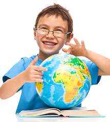 Image showing Little boy is examining globe