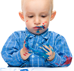 Image showing Little boy is playing with paints