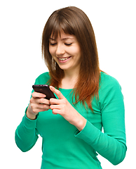 Image showing Young woman is typing sms message on her phone