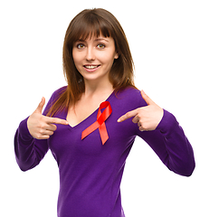 Image showing Woman is pointing to the red awareness ribbon