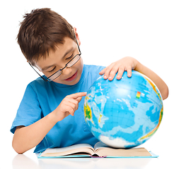 Image showing Little boy is examining globe