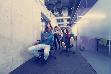 Image showing multiethnics business team racing on office chairs