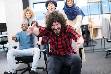 Image showing multiethnics business team racing on office chairs