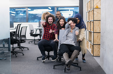 Image showing multiethnics business team racing on office chairs