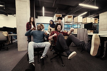 Image showing multiethnics business team racing on office chairs