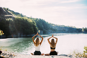 Image showing Young lesbian\'s couple exercizing yoga at riverside in sunny day