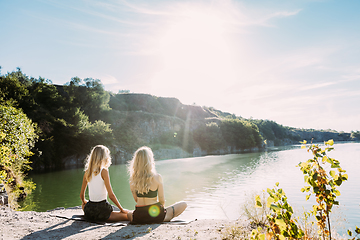 Image showing Young lesbian\'s couple exercizing yoga at riverside in sunny day