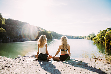 Image showing Young lesbian\'s couple exercizing yoga at riverside in sunny day