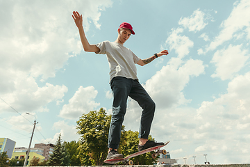 Image showing Skateboarder doing a trick at the city\'s street in sunny day