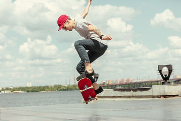 Image showing Skateboarder doing a trick at the city\'s street in sunny day