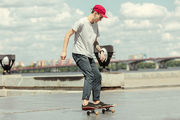 Image showing Skateboarder doing a trick at the city\'s street in sunny day