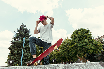 Image showing Skateboarder doing a trick at the city\'s street in sunny day