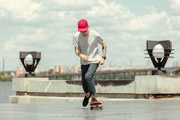 Image showing Skateboarder doing a trick at the city\'s street in sunny day