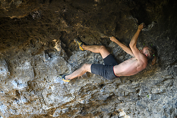 Image showing Young male climber bouldering a rock wall in a cave