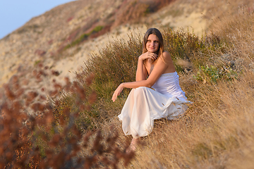 Image showing Beautiful girl sitting on a hillside at sunset