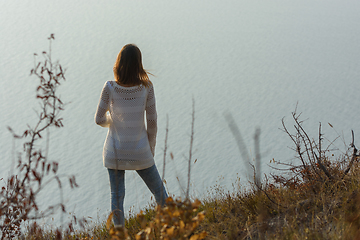 Image showing Girl stands on a hill and looks at the sea, rear view