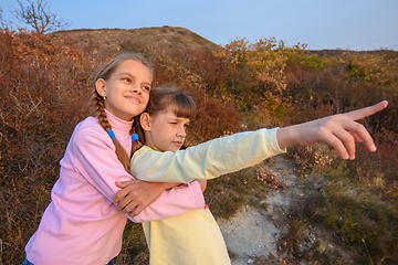 Image showing The girl hugs her sister who points her finger into the distance