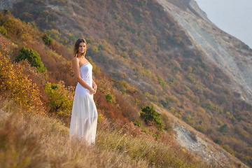 Image showing A beautiful girl stands on a hill by the sea