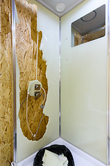 Image showing The back window of the shower stall is broken, and there\'s a bag of broken glass at the bottom