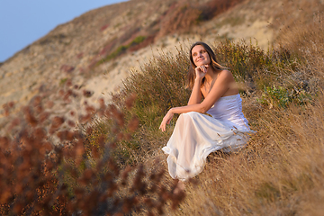 Image showing A girl in a white dress enjoys a beautiful view of the sunset