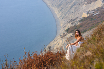 Image showing Beautiful girl at sunset sitting on a rocky beach