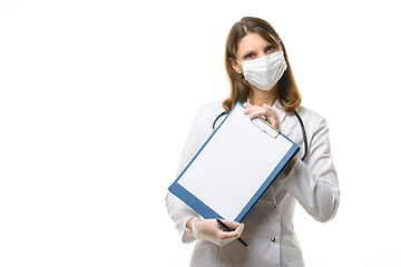 Image showing A girl doctor in a mask and gloves holds a tablet with a blank sheet of paper in her hands