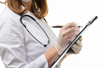 Image showing Hands of a doctor in gloves writes with a ballpoint pen in a tablet, close-up