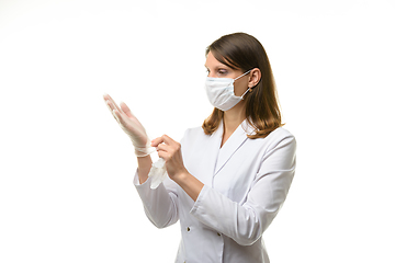 Image showing Girl doctor puts on transparent medical gloves on her hands