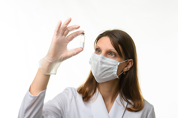 Image showing Doctor looks closely at the drug in a test tube, focusing on the test tube