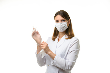 Image showing Girl doctor puts on transparent medical gloves on her hands and looks into the frame