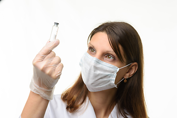 Image showing Girl doctor look at glass test tube with white powder, focus on test tube