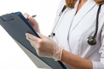 Image showing The doctor holds a tablet in his hands and writes down the symptoms of the disease