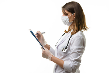 Image showing Girl doctor writes with a pen in a tablet computer on a sheet of paper