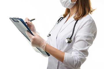 Image showing The doctor writes in a clipboard with a ballpoint pen