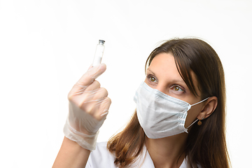 Image showing Girl doctor look at glass test tube with white powder, focus on girl