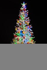 Image showing Festively decorated artificial white Christmas tree on a black background