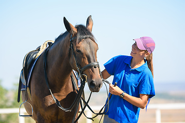 Image showing Happy beautiful girl looking at a horse on a warm summer day