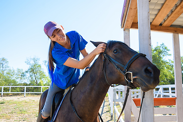 Image showing Girl after equestrian training joyfully looks at the horse\'s face