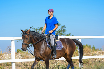 Image showing Pretty girl in casual clothes rides a horse